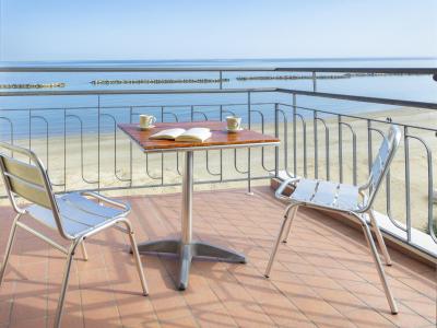 Sea view from a terrace with table and chairs.