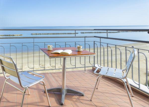 Sea view from a terrace with table and chairs.