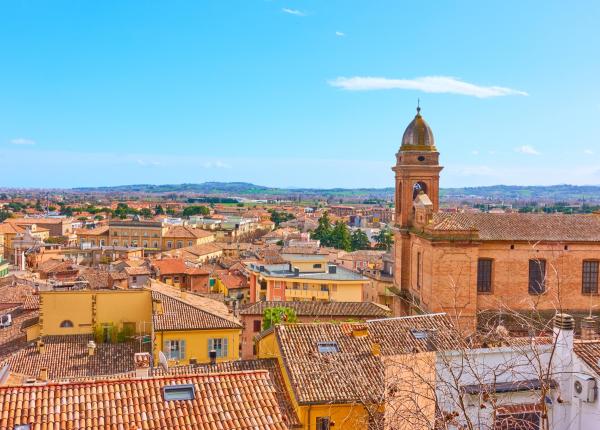 Panoramic view of an Italian city with rooftops and a bell tower.