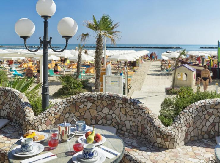 Spiaggia con ombrelloni, lettini e colazione vista mare.