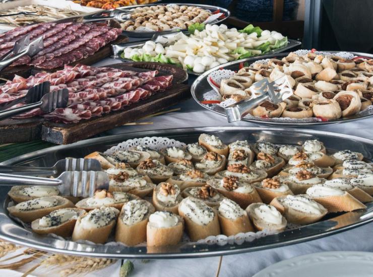 Buffet con salumi, formaggi e antipasti vari su vassoi.