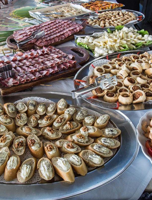 Buffet con salumi, formaggi e antipasti assortiti su vassoi.